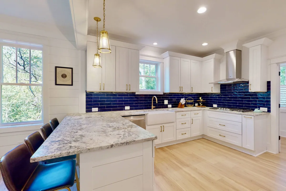 The gourmet kitchen boasts a central island with granite countertops, a striking blue backsplash, and high-end stainless steel appliances. The scene is set for both everyday meals and special celebrations, with ample space for guests to gather around while meals are prepared.