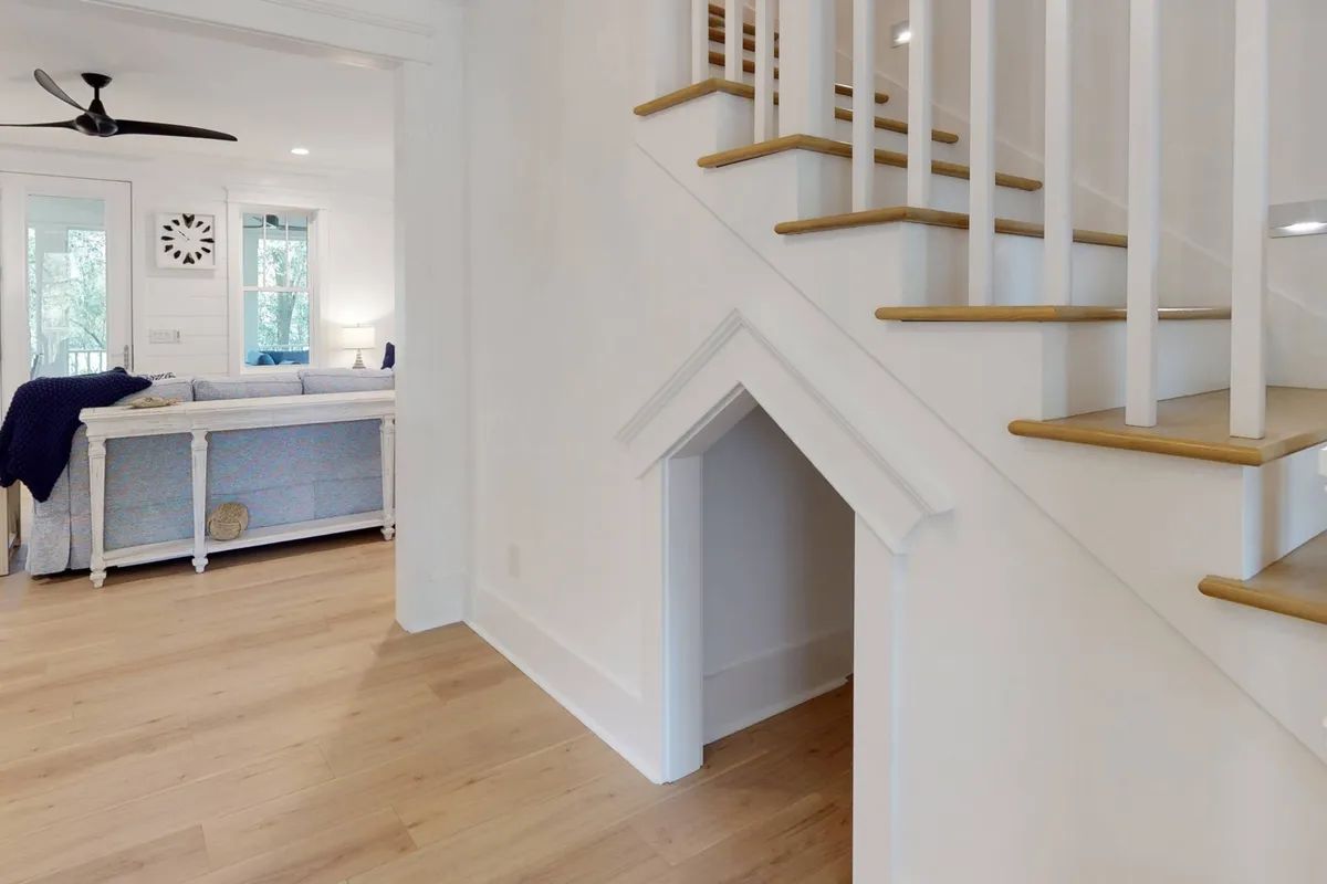 A view of the staircase with an inviting under-stair nook, adjacent to the living area. The nook offers a cozy, dedicated space beneath the stairs, ideal for a pet or quiet lounging.