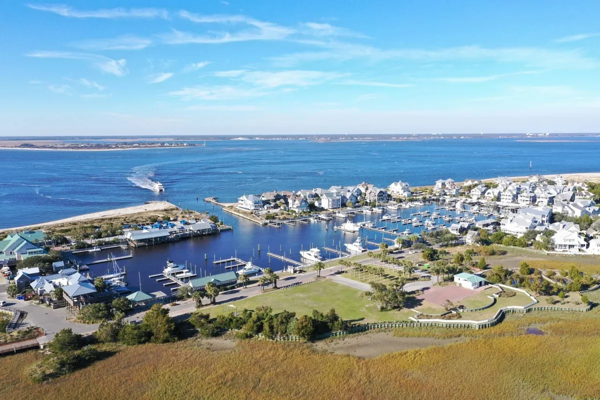 This image captures a tranquil marina scene, with boats docked along the waterway, houses lining the shore, and green space nearby. The view conveys a sense of proximity to the waterfront and easy access to local exploration and activities.