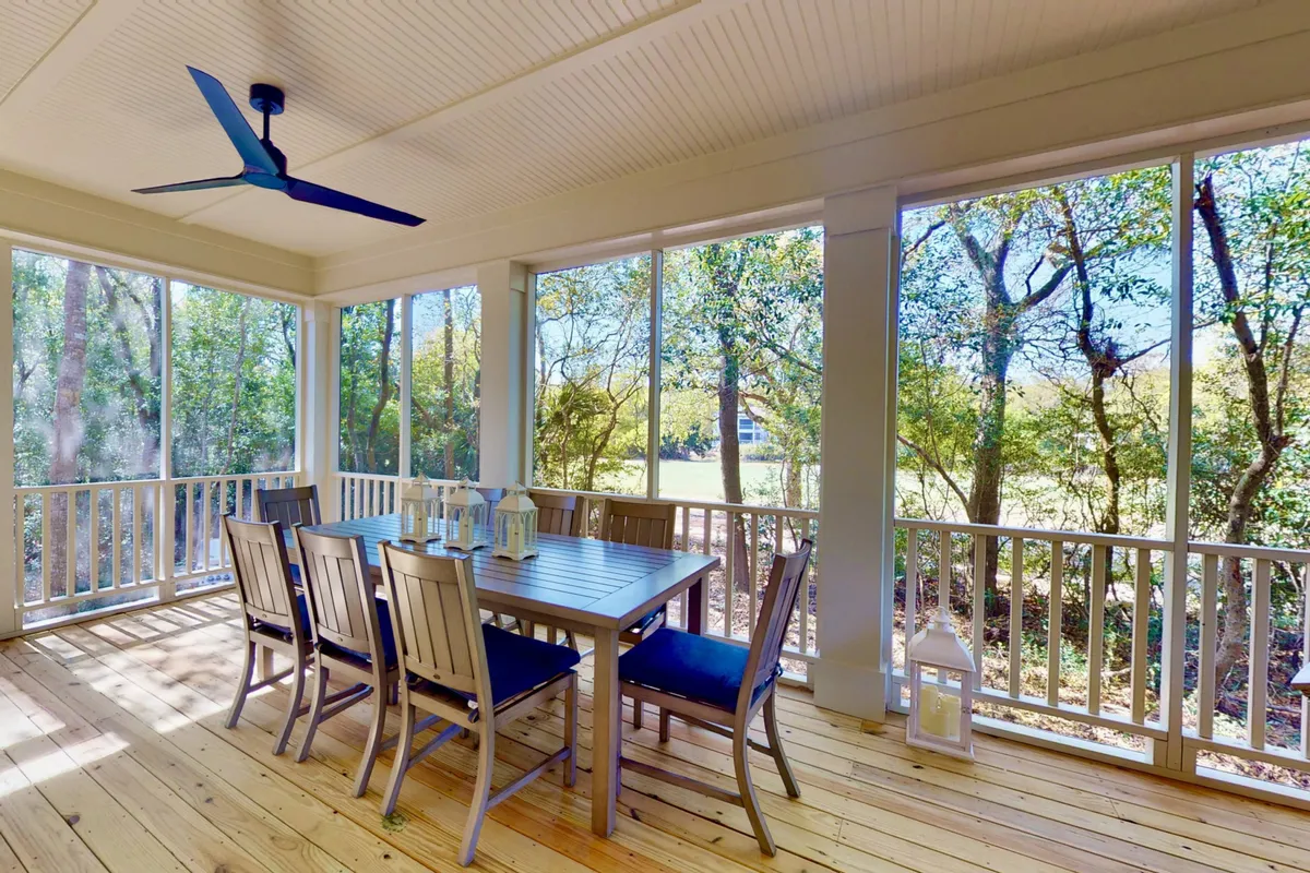 A bright dining area framed by large windows opens up to natural surroundings, with a spacious dining table set for communal meals. The space blends indoor comfort with outdoor views, creating an inviting atmosphere for both casual and formal gatherings.